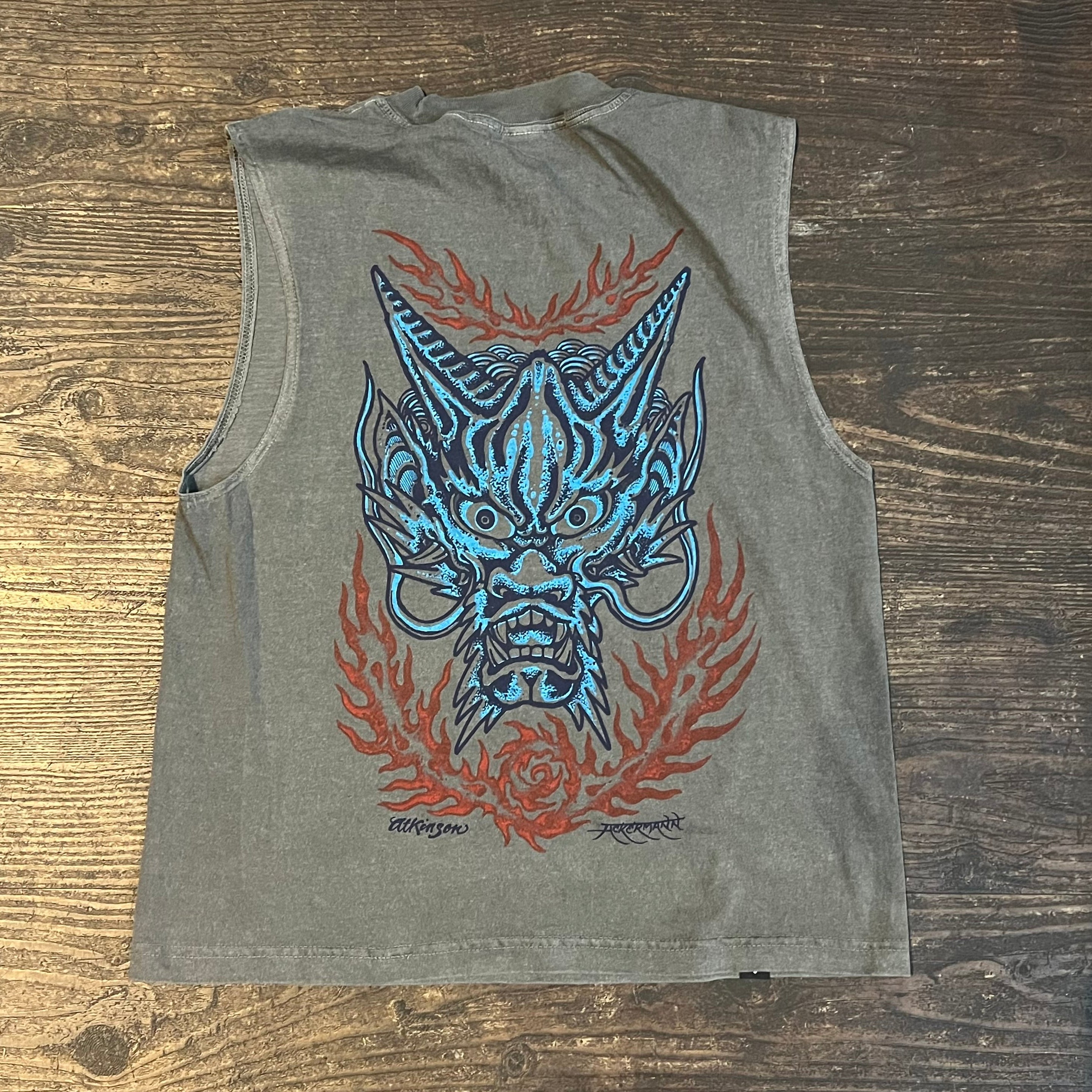 Gray t-shirt with a dragon design on a wooden surface
