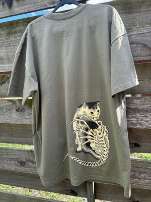 Olive green t-shirt with a graphic design of a skeleton cat on a wooden fence.