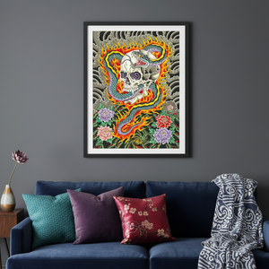 Framed colorful artwork of a dragon and skull on a gray wall above a blue sofa with patterned cushions.