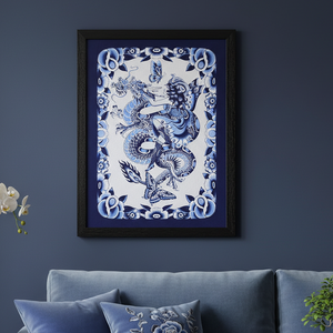 Framed artwork of a blue dragon on a white background, hanging above a blue sofa.