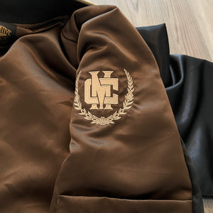 Lifestyle shot of satin bomber jacket draped over chair showing interior lining.